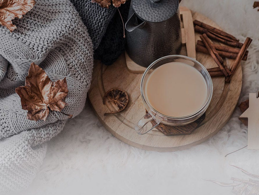Fallen autumn leaves on a blanket with a cup of coffee and cinnamon sticks.