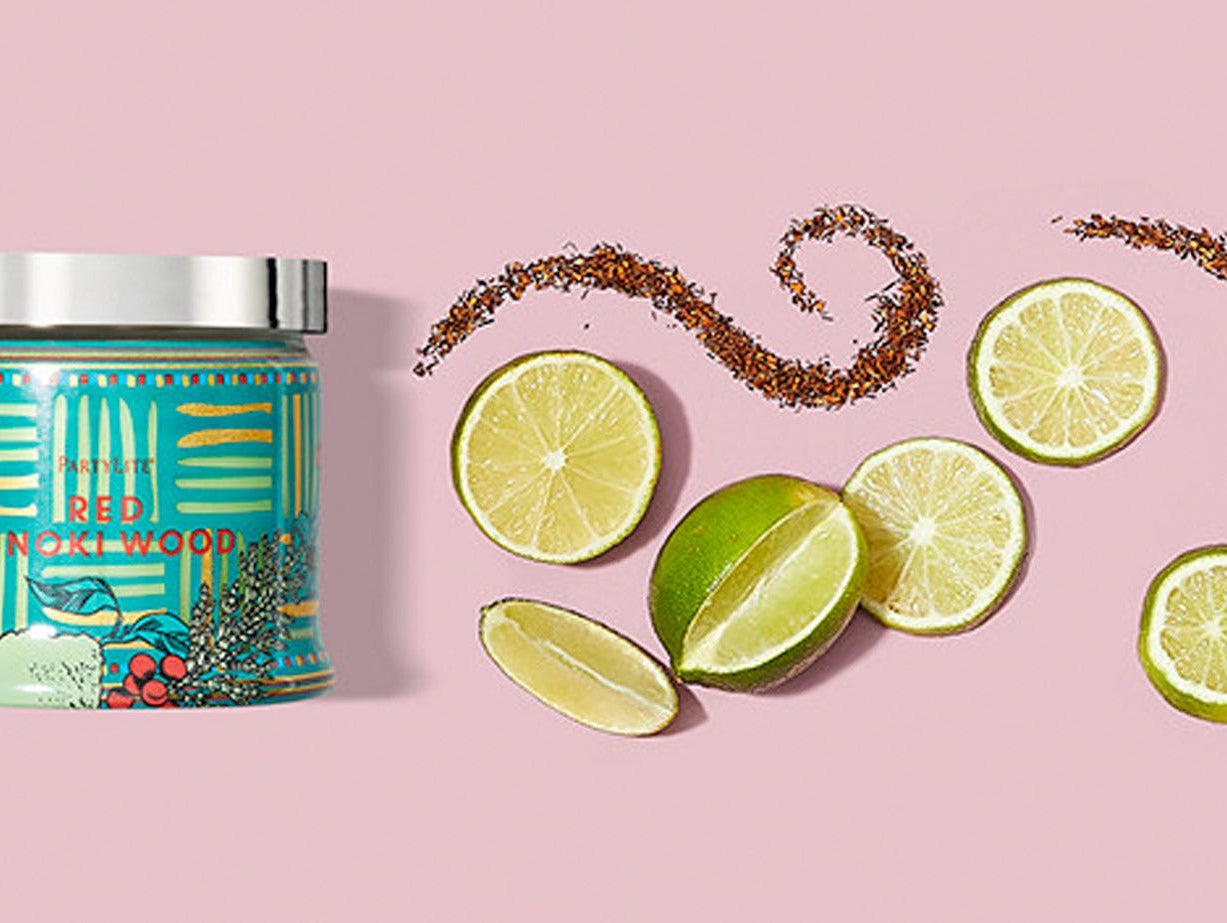 Red Hinoki Wood jar candle next to slices of lime.