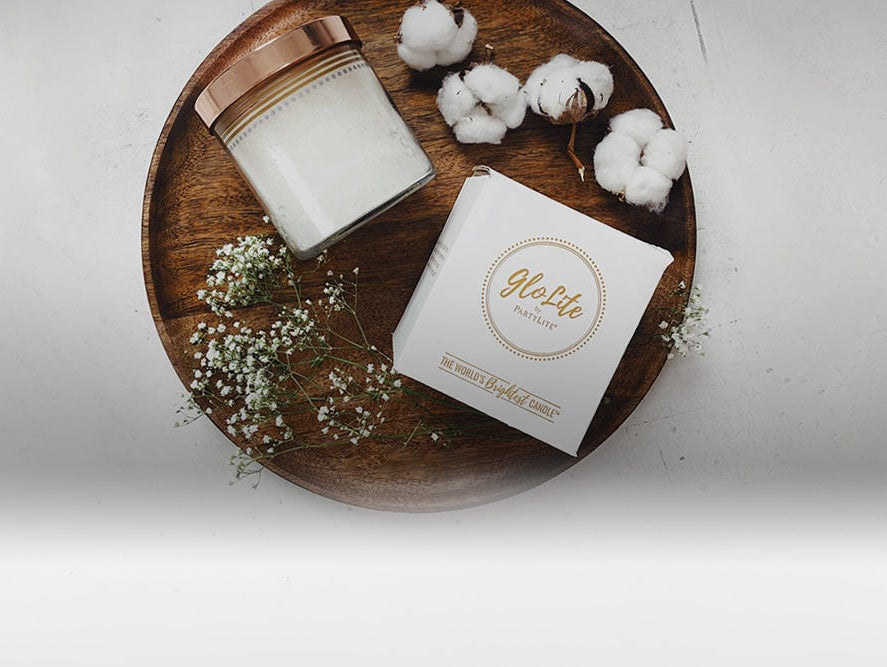 A white GloLite Candle and box displayed next to cotton balls.