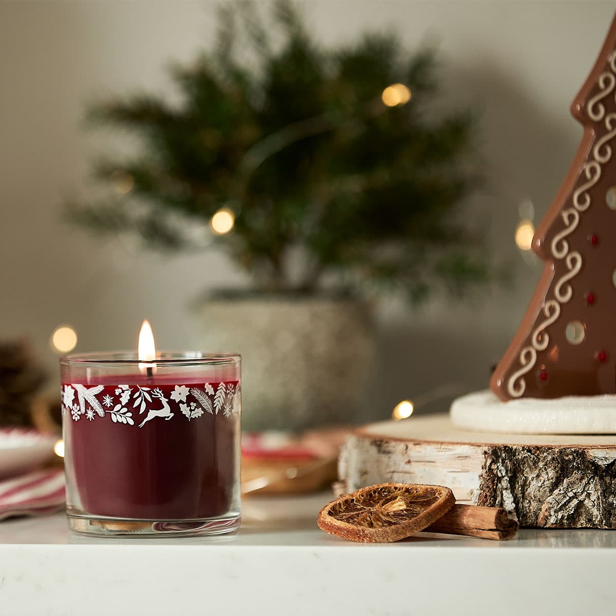 Bourbon Cherry Mini Jar Candle lit with a blurred background.