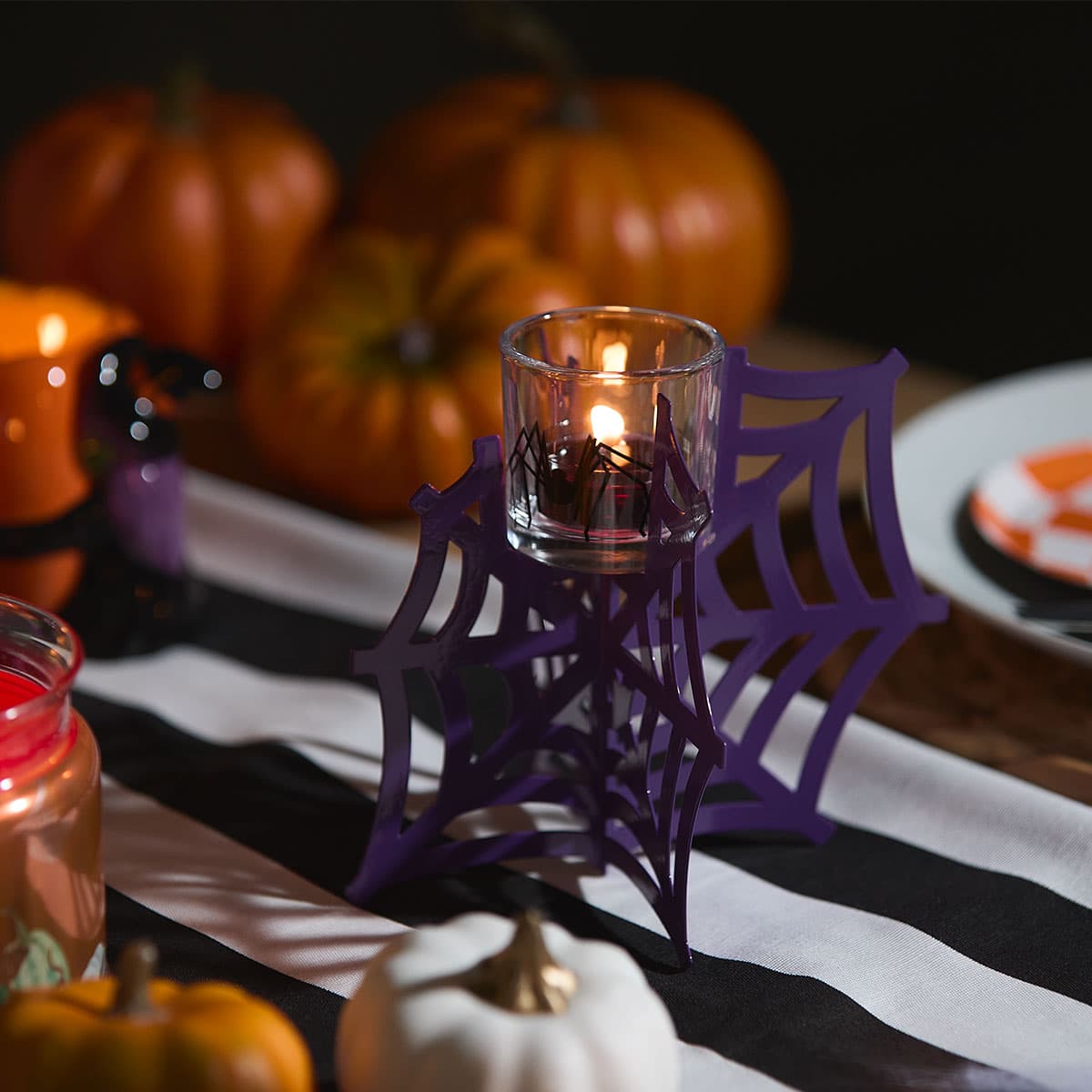 Tangled Web Tealight/Votive Holder with a purple web on a black and white stripy table runner.