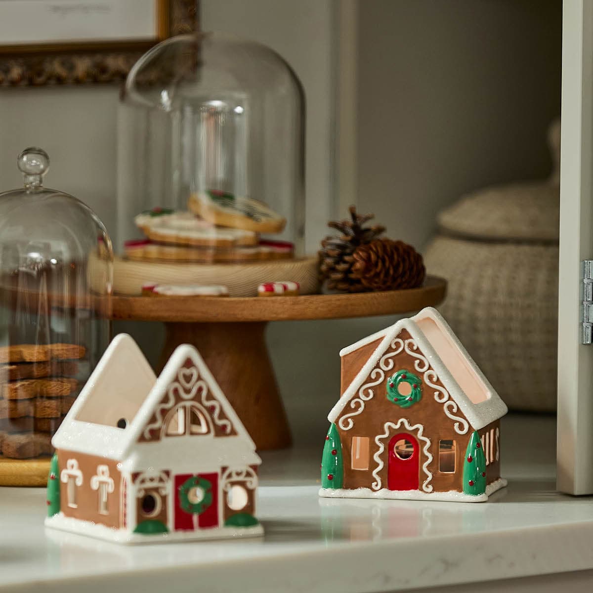 Gingerbread Village Tealight Holder Pair, cookie jar holders in the background set on a shelf.
