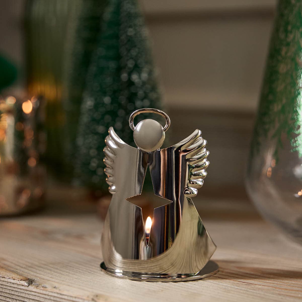 Star Angel Tealight/Votive Holder, polished silver-tone holder with a lit candle on a wooden surface.