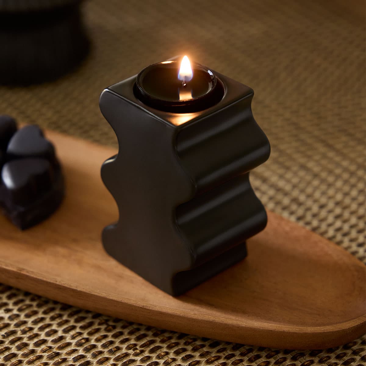 Curvy Black Tealight/SmartScents Holder with a lit tealight on a wooden tray.