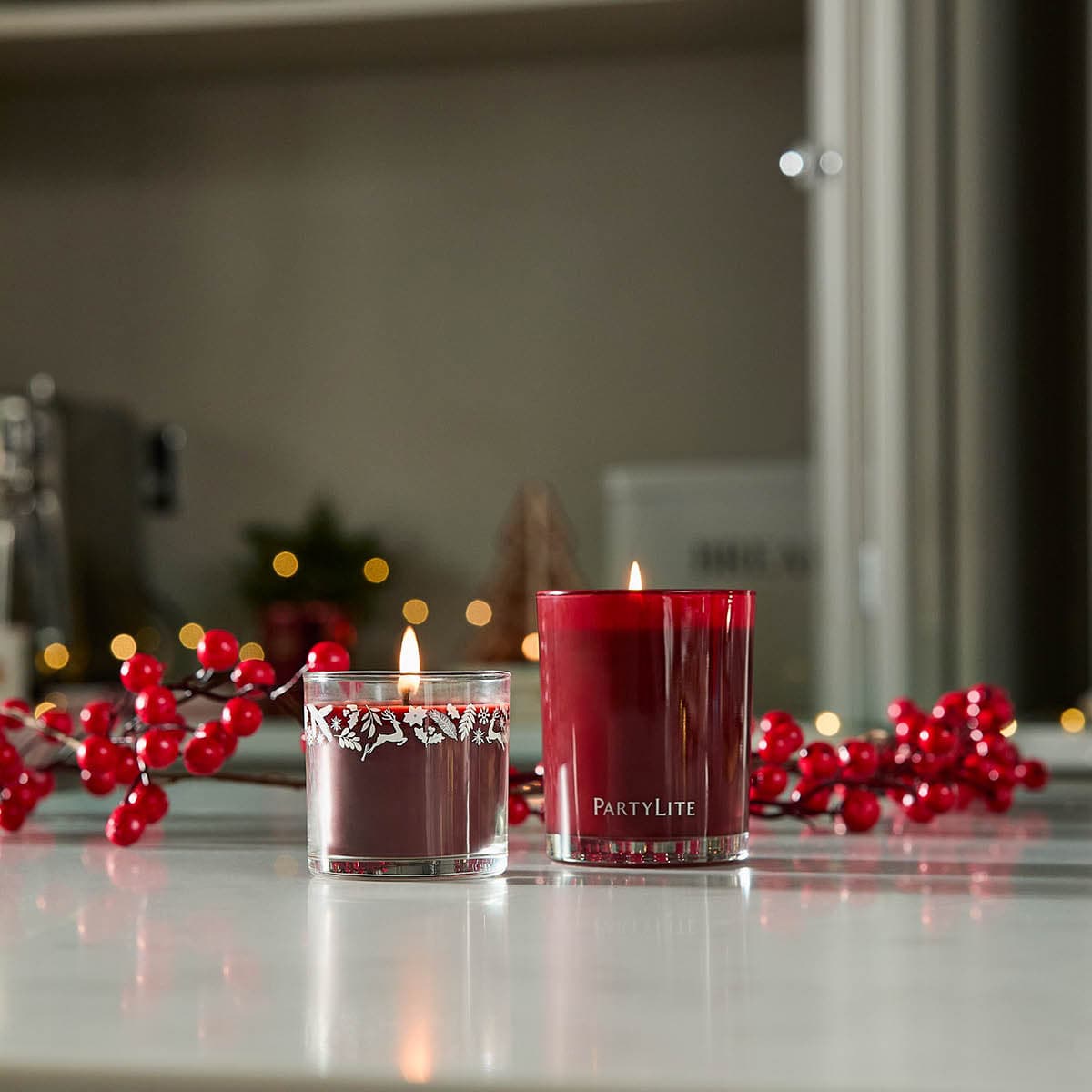 Bourbon Cherry Escential Jar candle lit next to Bourbon Cherry Mini Jar Candle on a light surface with red fairy lights in the background.
