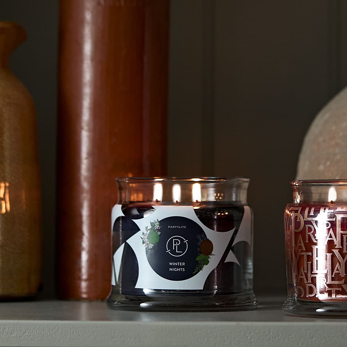 Winter Night 3-wick jar candle shown lit on a grey shelf.