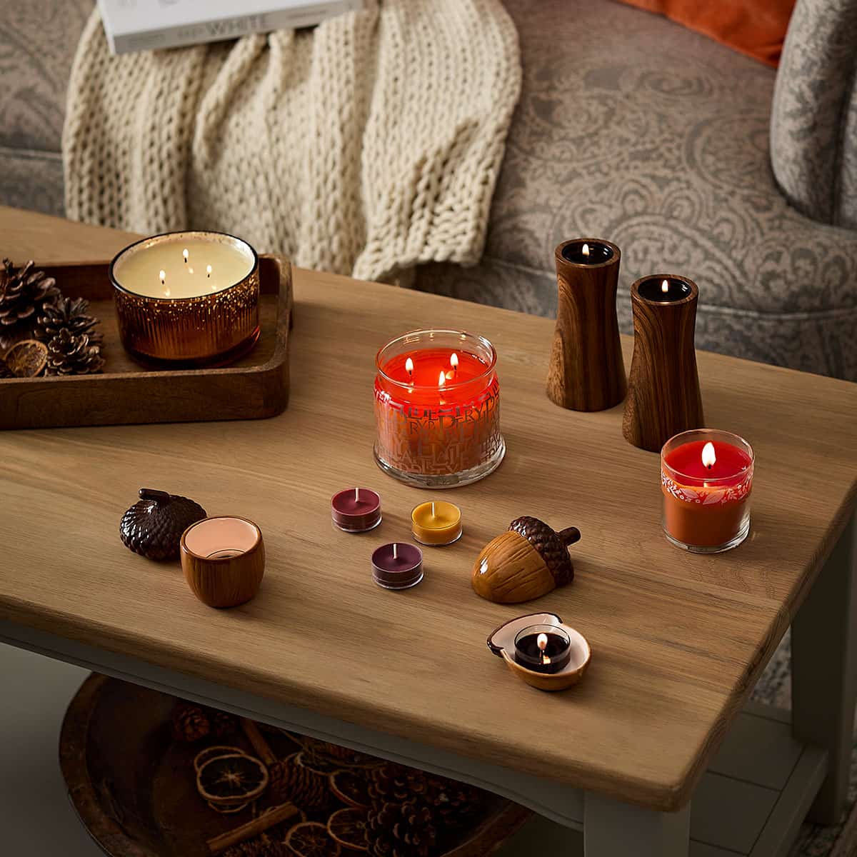 Leaves of Fun 3-Wick Jar Candle shown on a wooden coffee table with a Mini Jar lit, loose tealights unlit, lit tealights in holders and a 3-wick ripple jar on a wooden tray.