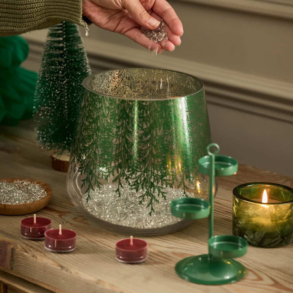 Lacy Green Hurricane shown with levelling beads, a green tealight tree and unlit tealights on a wooden surface.