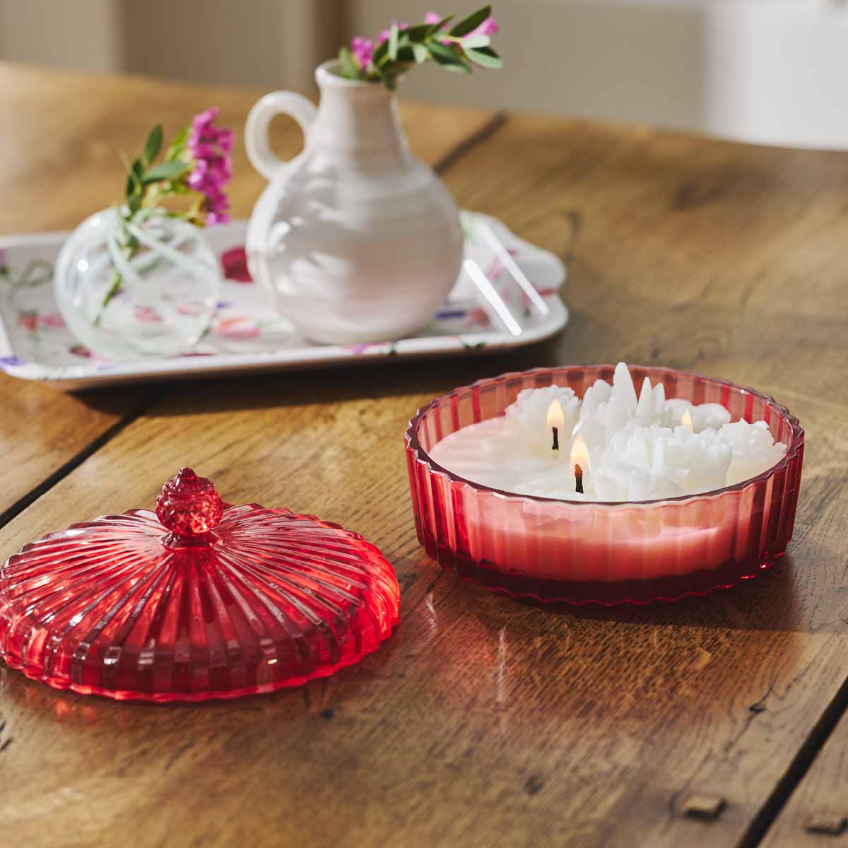 Garden Beauty Specialty Jar - Garden Party lit with the jar lid next to it on a wood table with a decorative tray with vases in the background.