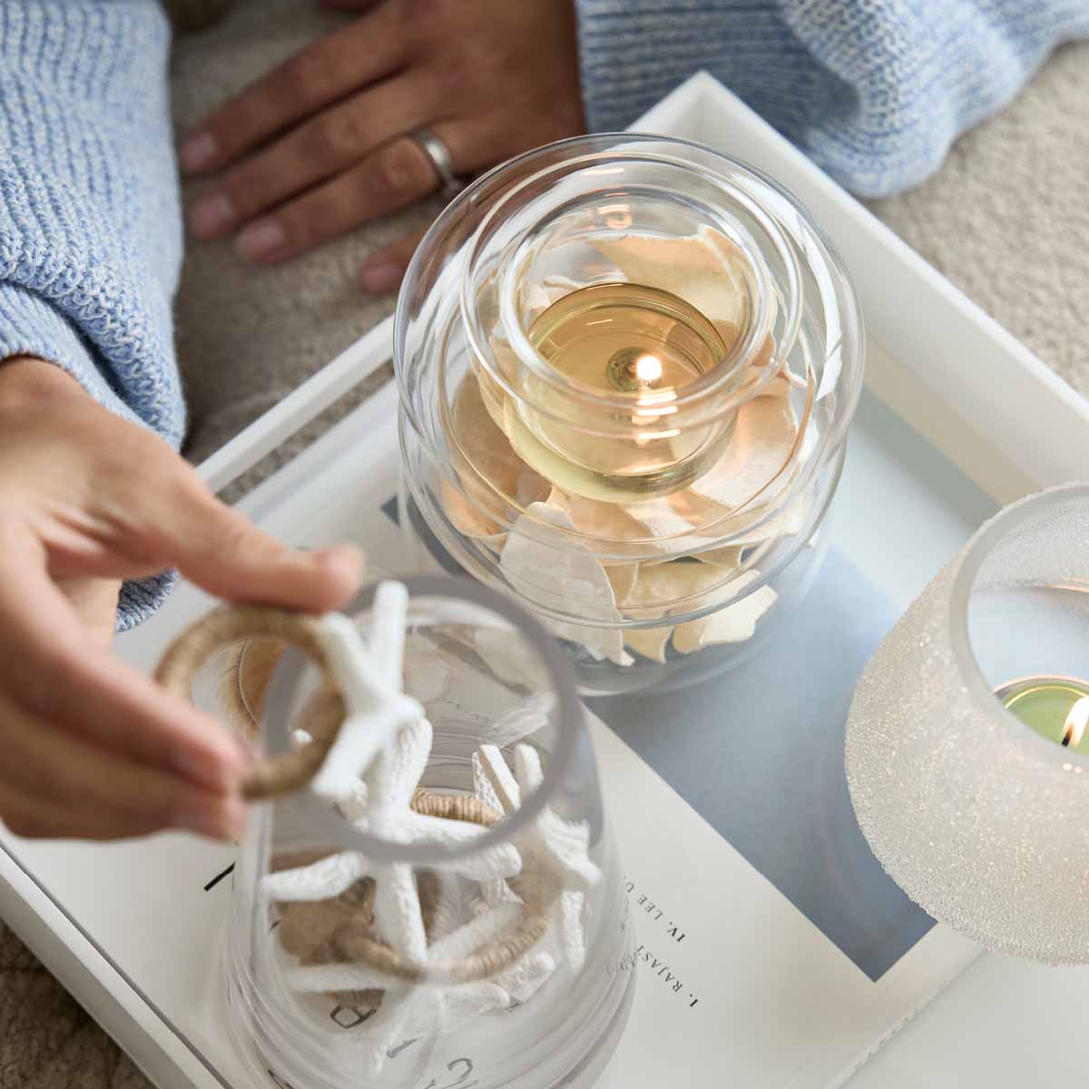 Illusion Tealight Holder with a lit tealights and decorative items around ti.