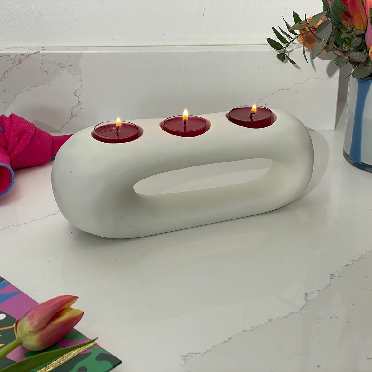 Modern Sculpt Tealight Centerpiece, with three lit tealights on a kitchen worktop surface.