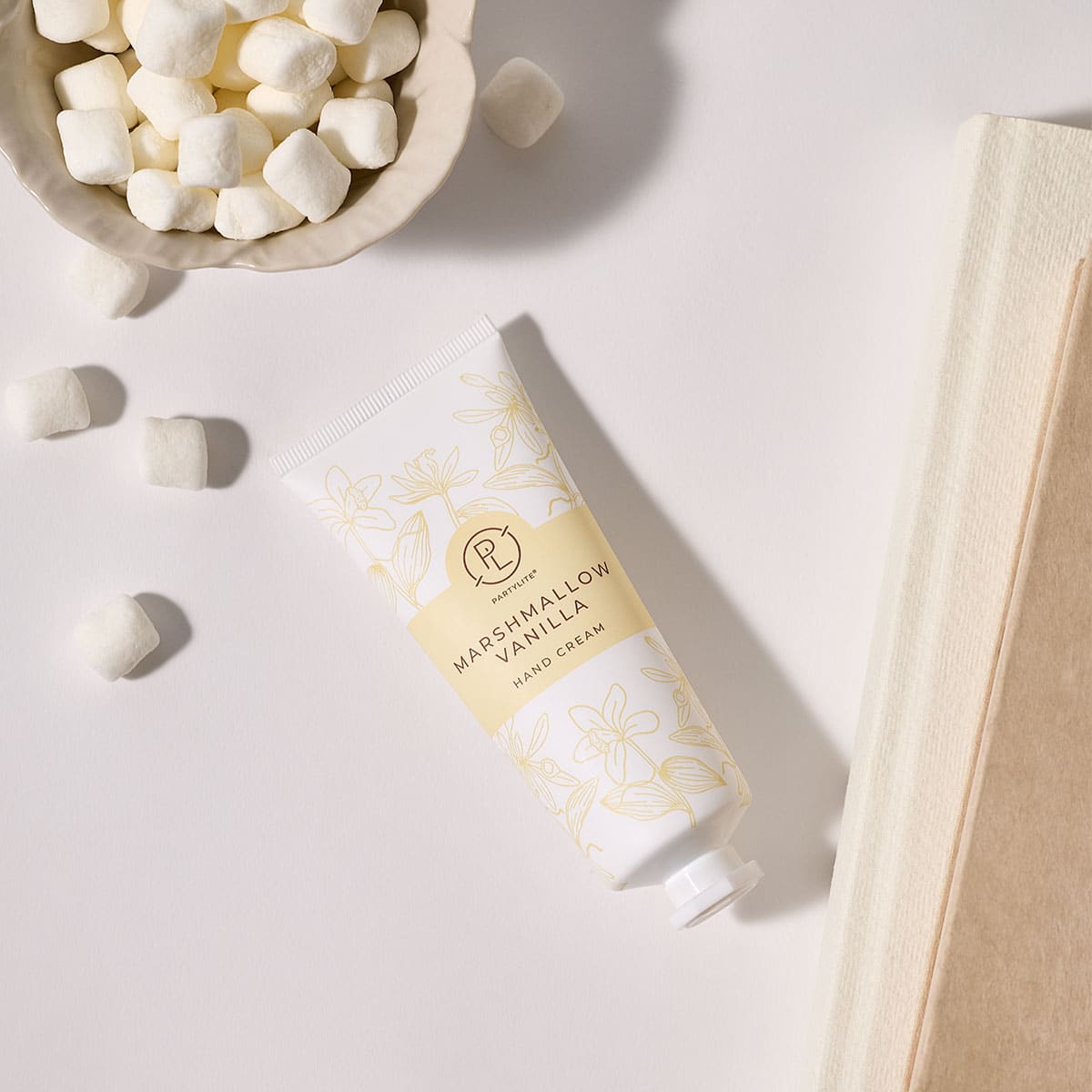 Marshmallow Vanilla Hand Cream with a bowl of small Marshmallows next to it on a white surface