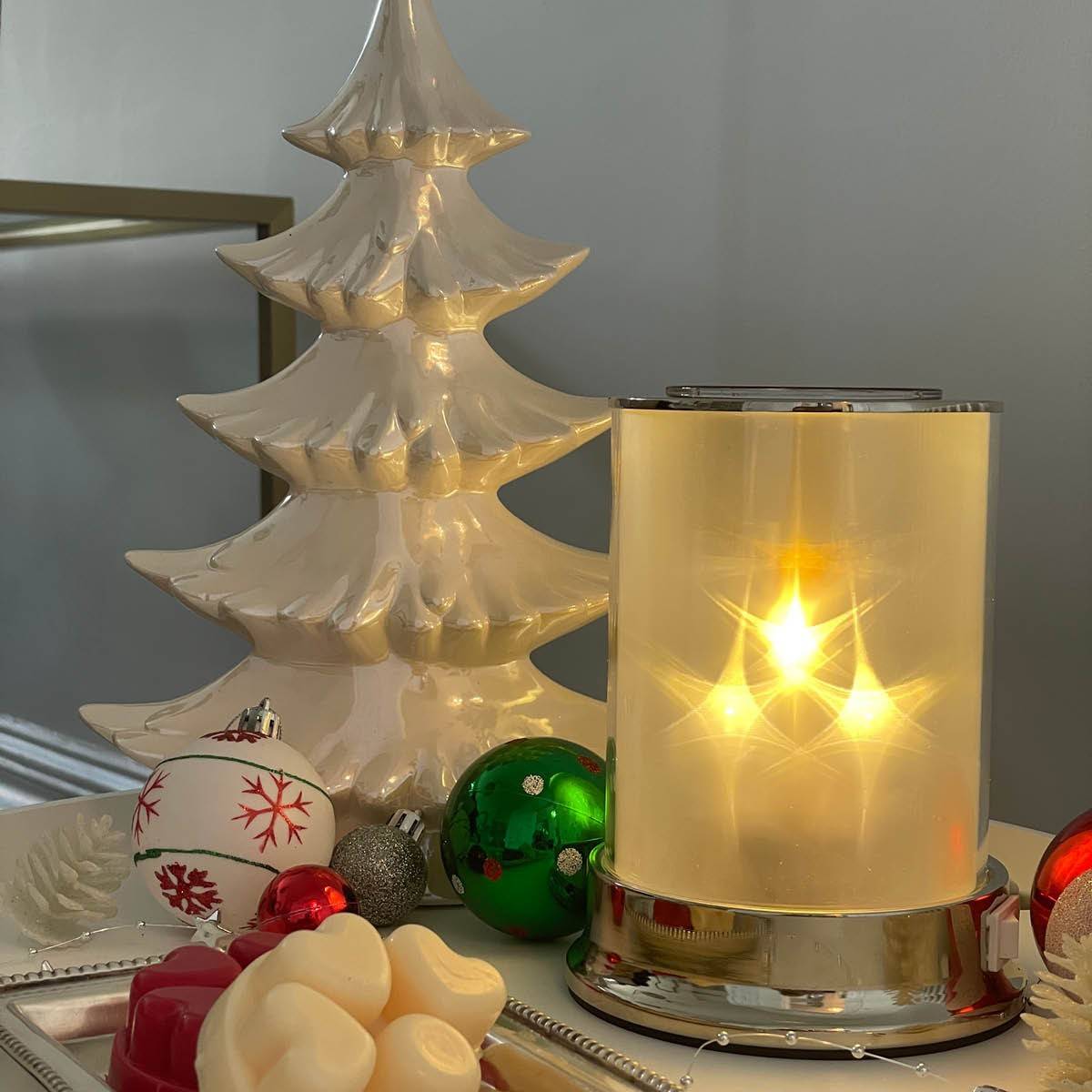 Starlight ScentGlow® Warmer next to a wax melt, holiday ornaments and a white ceramic tree.