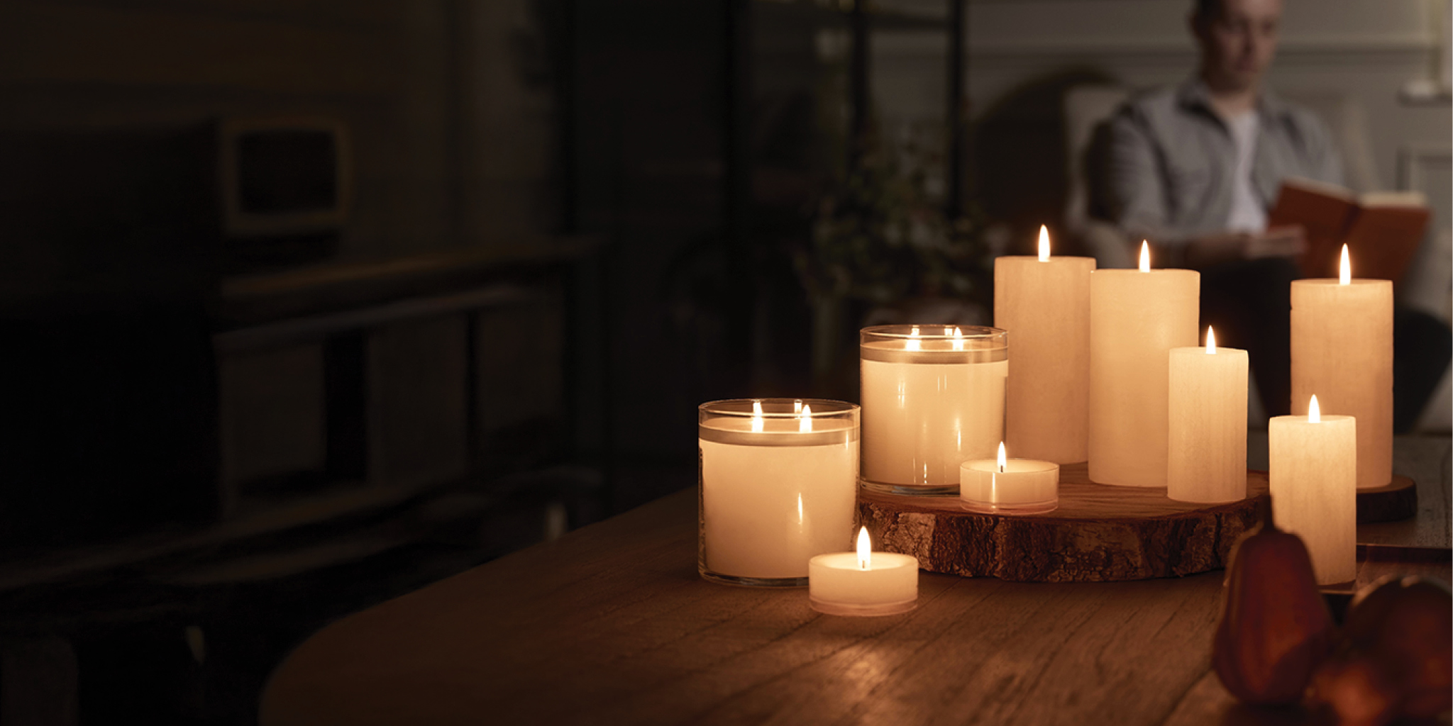 GloLite Pillars, Jar Candles, and Large Tealights on a table in a darkened room.