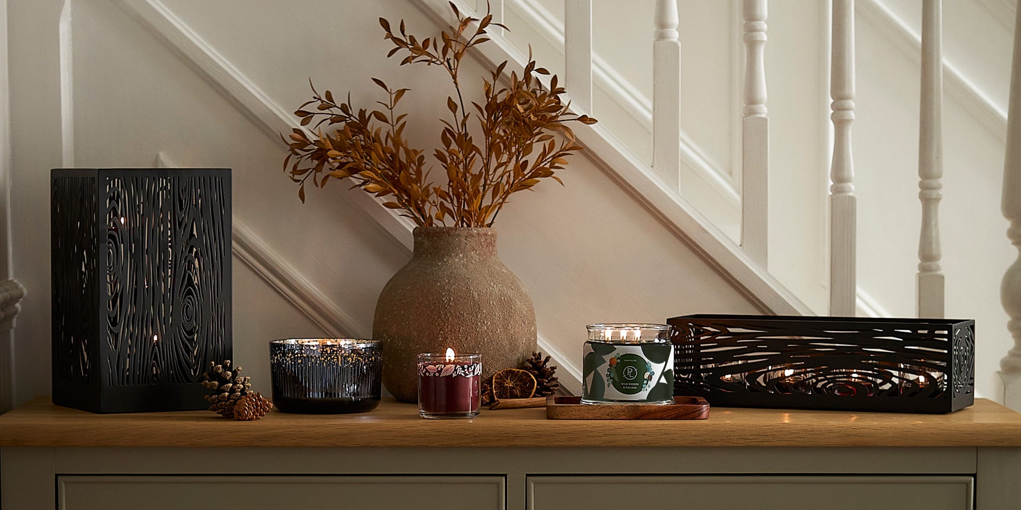 Sideboard with a wood grain hurricane, assorted jar candles, and a wood grain centerpiece.