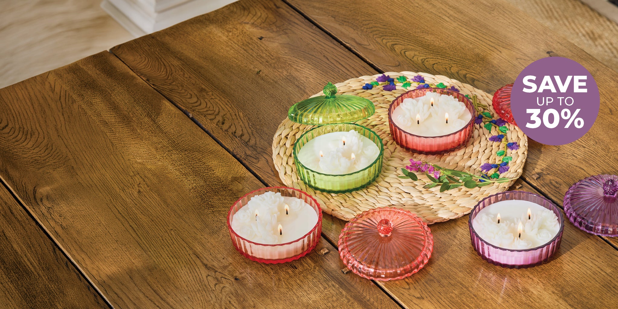 Set of colorful candles with lids on a wooden surface, with a discount label in the corner.