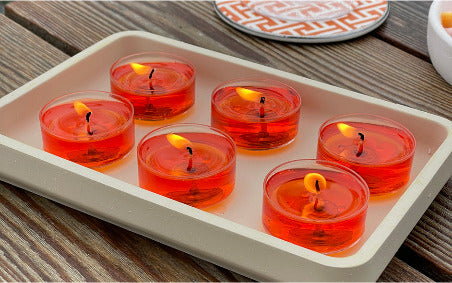 Red candles in glass holders on a white tray with a wooden surface background