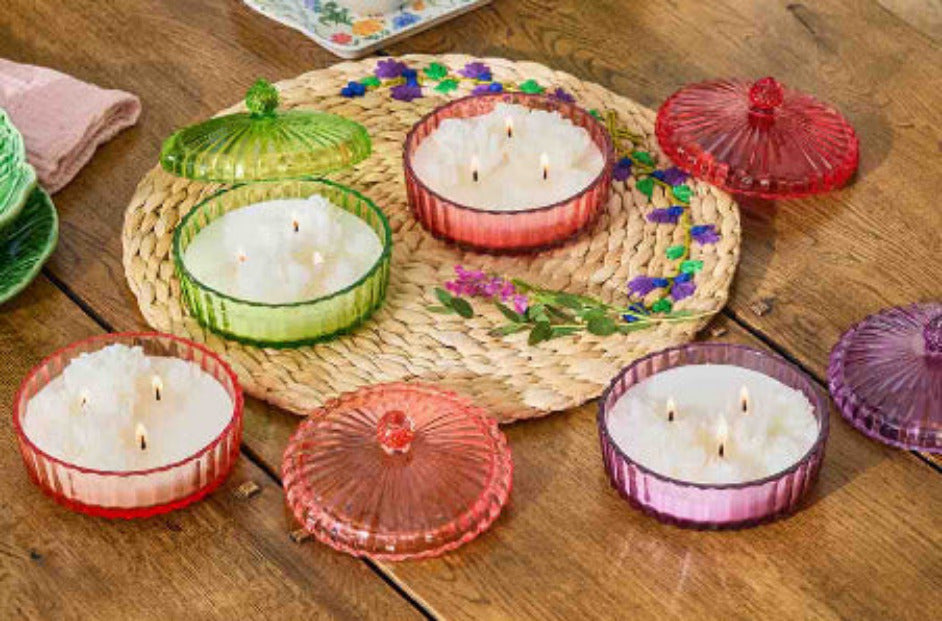Collection of Garden Beauty Specialty Jar candles with lids on a woven mat on a wooden surface