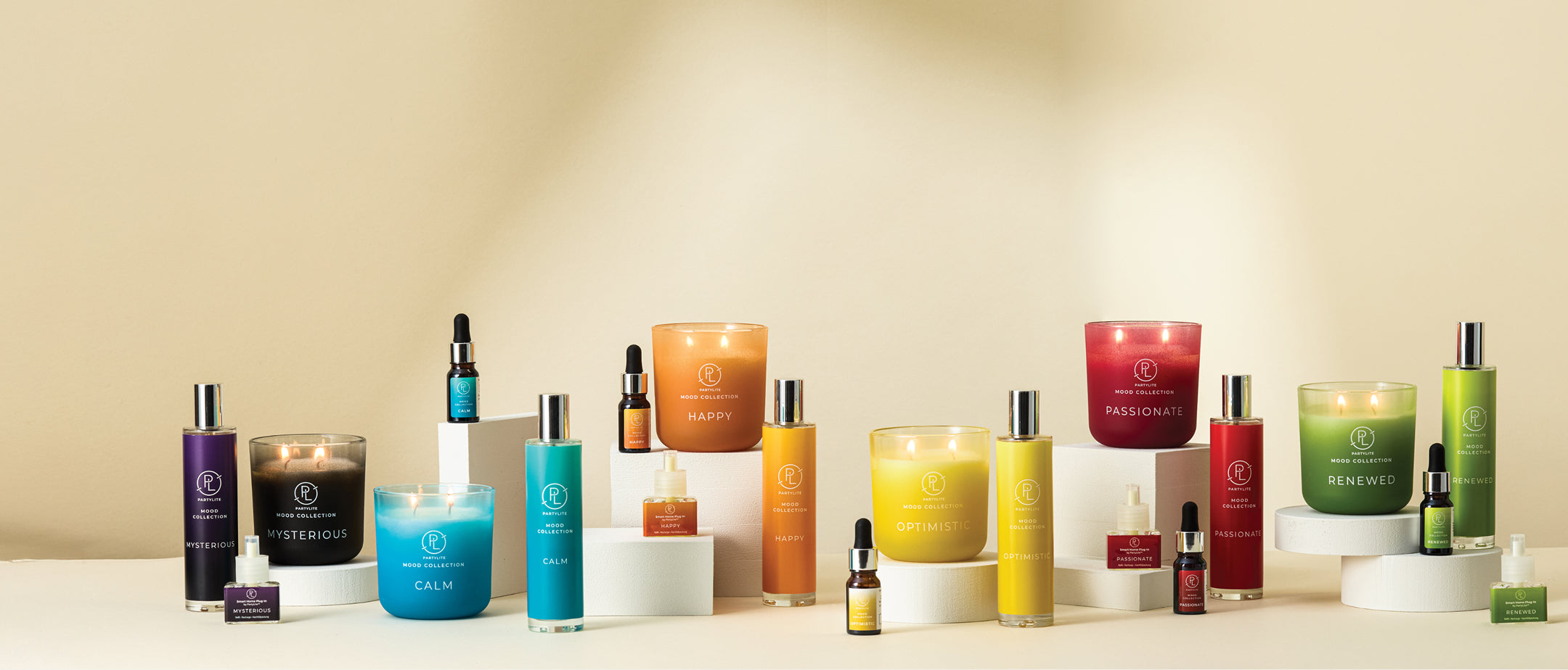 Assorted Mood Collection items. Jar Candles, Room Sprays, Fragranced Oils, and Smart Home Plug-in Refills. All displayed on a tan background. 